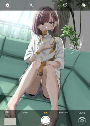  animal barefoot brown_eyes brown_hair closed_mouth commentary_request couch day fake_phone_screenshot fake_screenshot feline female highres holding holding_animal holding_cat indoors legs looking_at_viewer original plant potted_plant smile solo soragane_(banisinngurei) 